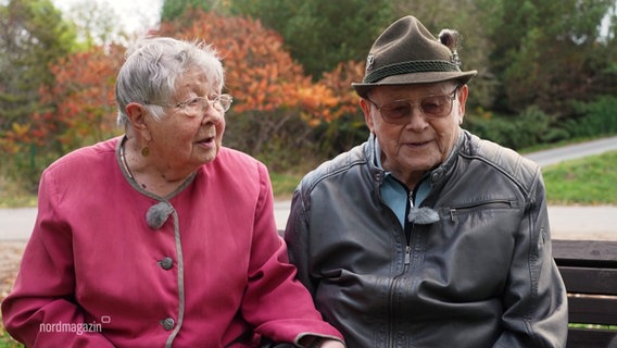 Das Ehepaar Christel und Gerhard Oppelt sitzt auf einer Bank vor seinem Haus. © Screenshot 