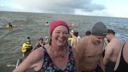 Eine lachende Frau entsteigt beim Neujahrsanbaden der kalten Nordsee. © Screenshot 