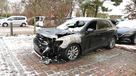 Ein abgebranntes Auto auf einem Hotelparkplatz. © Screenshot 