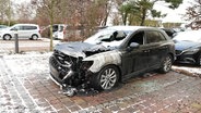 Ein abgebranntes Auto auf einem Hotelparkplatz. © Screenshot 