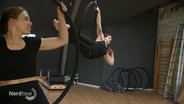 Zwei Frauen beim Aerial Hoop Training: Trainerin Sarah Lemanzki zeigt eine Figur, während eine Schülerin zuschaut. © Screenshot 