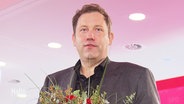 Lars Klingbeil (SPD) hält einen Blumenstrauß in der Hand. © Screenshot 