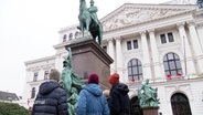 Eine Gruppe Menschen steht vor dem Altonaer rathaus und schaut auf ein Reiter-Standbild. © Screenshot 