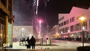 Mehrere Menschen schauen sich Feuerwerk in einer Stadt an. © Screenshot 