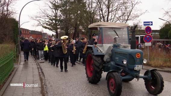 Mit Traktor und Blaskapelle ziehen Schüler und Lehrer in das neue Gebäude. © Screenshot 