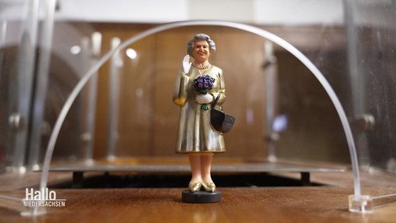 Eine Figur von Queen Elizabeth II. steht auf einer alten Kino Kasse. © Screenshot 