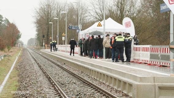 Am neuen Bahnsteig im Industriepark Schwerin stehen mehrere Menschen und feiern die Eröffnung. © Screenshot 