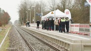 Am neuen Bahnsteig im Industriepark Schwerin stehen mehrere Menschen und feiern die Eröffnung. © Screenshot 