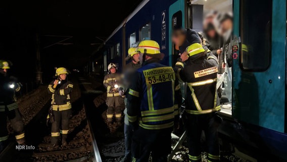 Einsatzkräfte der Feuerwehr evakuieren Menschen aus einem Zug. © Screenshot 