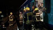 Einsatzkräfte der Feuerwehr evakuieren Menschen aus einem Zug. © Screenshot 