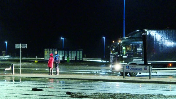 Zwei Personen stehen auf einem überschwemmten Parkplatz. © Screenshot 