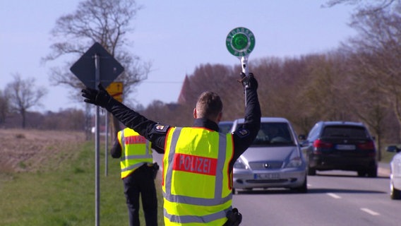 Ein Polizist ist von hinten zu sehen, wie er ein Fahrzeug rauszieht. © Screenshot 