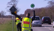 Ein Polizist ist von hinten zu sehen, wie er ein Fahrzeug rauszieht. © Screenshot 