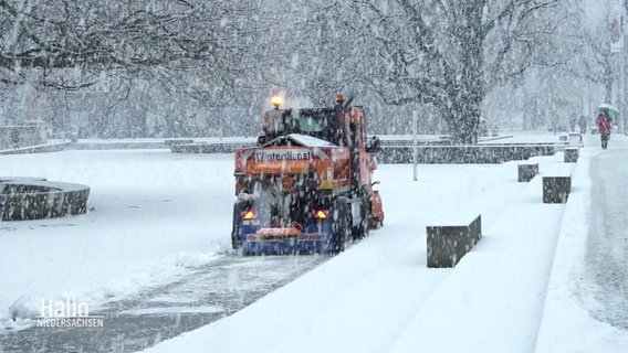 Im Schneetreiben fährt ein Räumfahrzeug vom Winterdienst. © Screenshot 