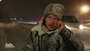 Reporter Tino Nowitzki mit eingeschneiter Jacke, Mütze und Mikrofon draußen vor Ort im Harz. © Screenshot 