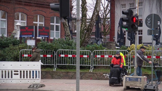 Eine Frau im Rollstuhl wartet vor einen roten Fußgängerampel. © Screenshot 