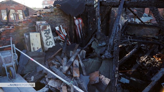 Nach einem Brand große Schäden an einem Gebäude: Verkohlte Dachbalken, angeschmorte historische Bahnschilder, Signalschilder und Schutt im ehemaligen Lager des Eisenbahnmuseums in Schwerin. © Screenshot 