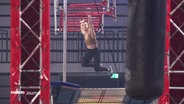 Beim Ninja Warriors Turnier in Hamburg: Eine Frau hangelt sich an einer Sprossenwand entlang. © Screenshot 