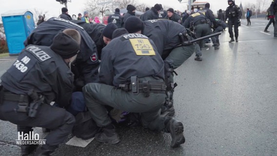 Polizisten fixieren eine Person am Boden. © Screenshot 