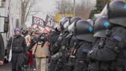 Protestierende laufen an einem Polizeispalier vorbei. © Screenshot 