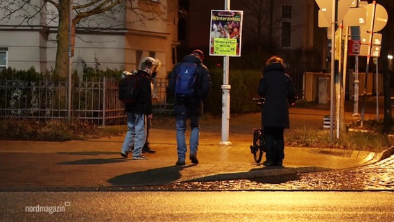 Menschen stehen an einer Straße. © Screenshot 