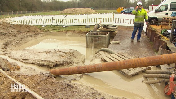 Auf einer Baustelle führt ein Bohrrohr in einen schlammigen Boden mit mehreren Pfützen. © Screenshot 