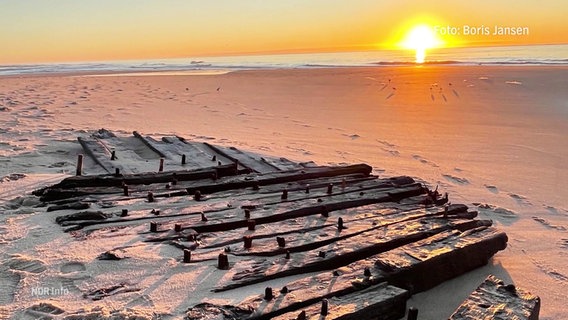 Ein im Strand halb vergrabenes Schiffswrack bei Sonnenuntergang © Screenshot 