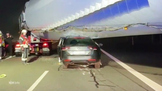 Ein PKW steckt an einer Unfallstelle auf einer Autobahn unter einem Windkraftflügel fest, der auf einem Schwerlasttransporter geladen ist. © Screenshot 