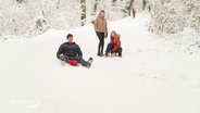 Zwei Personen rodeln einen schneebedeckten Hügel hinunter. © Screenshot 