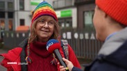 Eine Frau mit bunter Strickmütze wird interviewt © Screenshot 