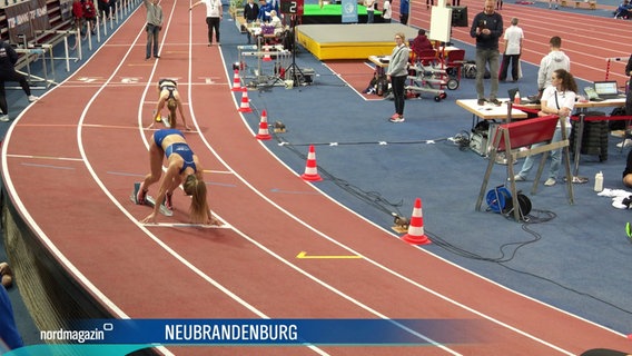 Bei einer Hallenmeisterschaft in Leichtathletik stehen Läuferinnen in ihren Startpositionen auf den Bahnen. © Screenshot 