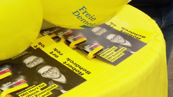 FDP-Wahlkampf-Stand mit einem Tisch mit Karten und gelben Luftballons. © Screenshot 