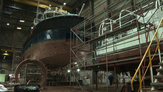 Ein Schiff liegt in einem Trockendock in einer Werft. © Screenshot 