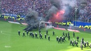 Einsatzkräfte der Polizei stürmen den Rasen des Volksparkstadions, weil dort Pyrotechnik gezündet wurde. © Screenshot 