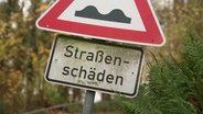 Ein Schild weist auf Straßenschäden hin. © Screenshot 