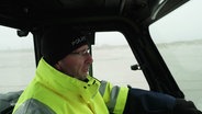 Ein Polizeibeamter in einem Fahrzeug am Strand. © Screenshot 