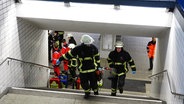 Feuerwehleute tragen Materialien vom Einsatzort fort. © News5 