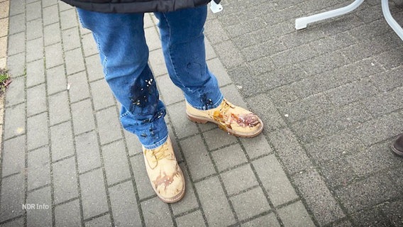 Blick auf die beschmutzten Hosenbeine und Schuhe eines Mannes nach einem Eierwurf. © Screenshot 