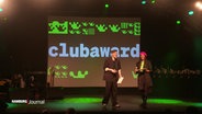 Zwei Personen auf der Bühne auf der "clubaward" zu lesen ist. © Screenshot 