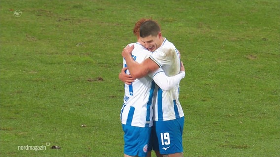 Zwei Spieler des FC Hansa Rostock umarmen sich auf dem Platz. © Screenshot 