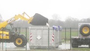 Ein Radlader lädt den Inhalt seiner Baggerschaufel in einen größeren Container ab. © Screenshot 