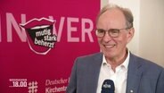 Ralf Meister, Landbischof von Niedersachsen, vor pinken Stellwand im Interview © Screenshot 