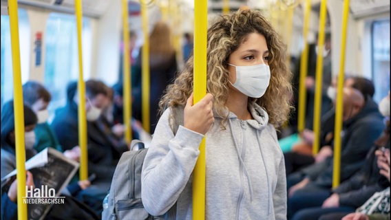 Während der Corona-Pandemie steht eine junge Frau mit FFP2-Maske in einer gut gefüllten Straßenbahn. © Screenshot 