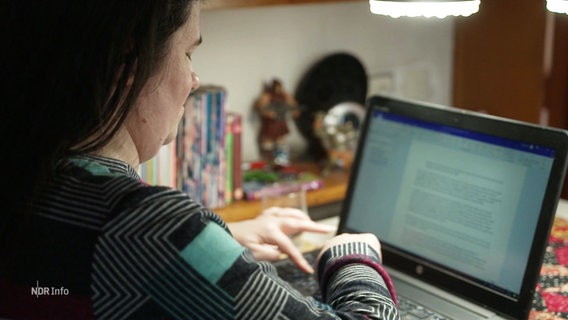 Eine Frau sitzt am Küchentisch und tippt auf einer Laptop-Tastatur. © Screenshot 