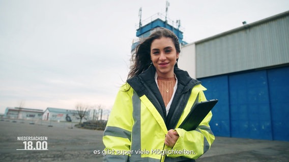 Eine junge Frau in Warnweste und mit Tablet auf einem Flugplatz. © Screenshot 