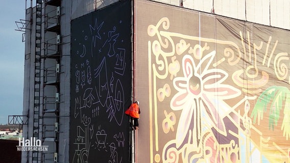 Ein Fassadenkletterer bringt am Turm der Martktkirche in Hannover ein großes Banner an. © Screenshot 