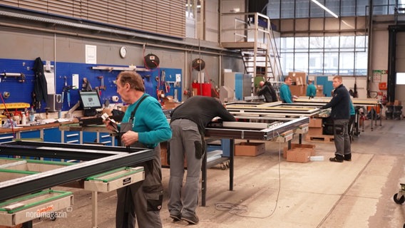 Mitarbeitende in einer Werkstatt für Fensterbau. © Screenshot 