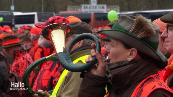 Eine Jägerin stößt bei einer Demonstration der Landesjägerschaft in ihr Horn. © Screenshot 