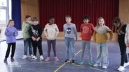 Mehrere Schülerinnen und Schüler stehen in einer Sporthalle. © Screenshot 