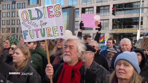 Demonstranten in der Hamburger Innenstadt, ein älterer Mann mit einem bunten Schild: "Oldies for future / Oldies gegen Rechts". © Screenshot 